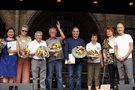Die mit der Urkunde "München dankt" geeherten Mitglieder von Selbsthilfegruppen stehen auf der Bühne des Selbsthilfetages und halten Blumensträuße und die Urkunden in den Händen. Daneben steht Matthias Winter vom Sozialreferat München
