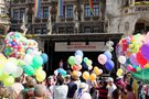 Selbsthilfetag auf dem Marienplatz. Viele Menschen stehen vor einer Bühne und halten bunte Luftballons. Im Hintergrund ist die Bühne zu sehen, auf der ein Banner vom Selbsthilfezentrum München zu sehen ist